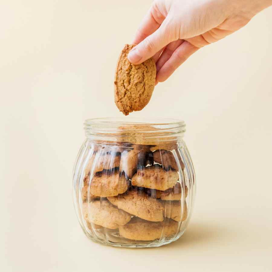 Persoon pakt een koekje uit een glazen pot gevuld met cookies. Lees meer over privacy, gebruikersverklaring in het cookiebeleid.